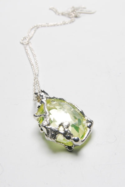 Pendant set with a beautiful peridot stone. The silver setting is made with an experimental process and makes an unusual organic shape around the refined stone.