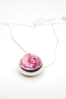 Laus silver pendant set with a large pink ruby that moves freely inside the silver band surrounding it